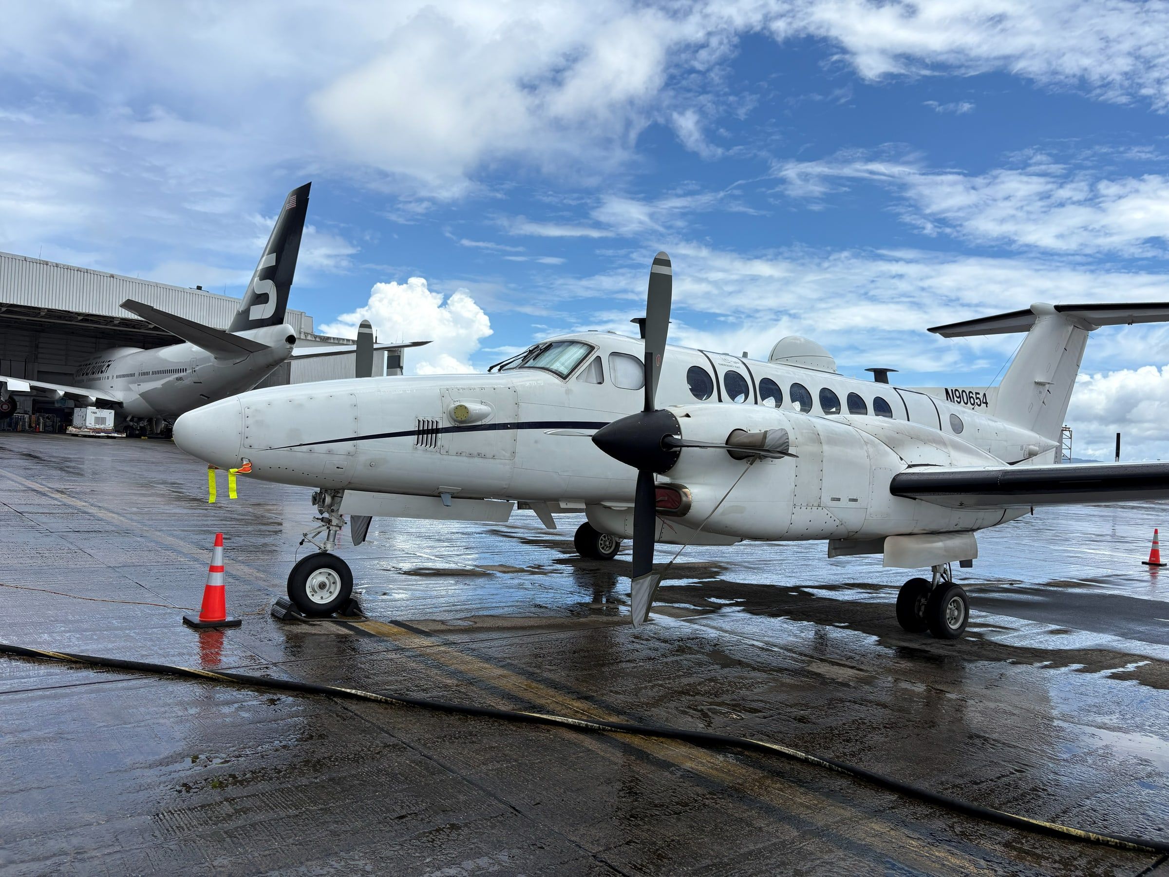 Wellman Aviation Services King Air 350ER testbed on a wet ramp under a dramatic sky during a Pacific deployment